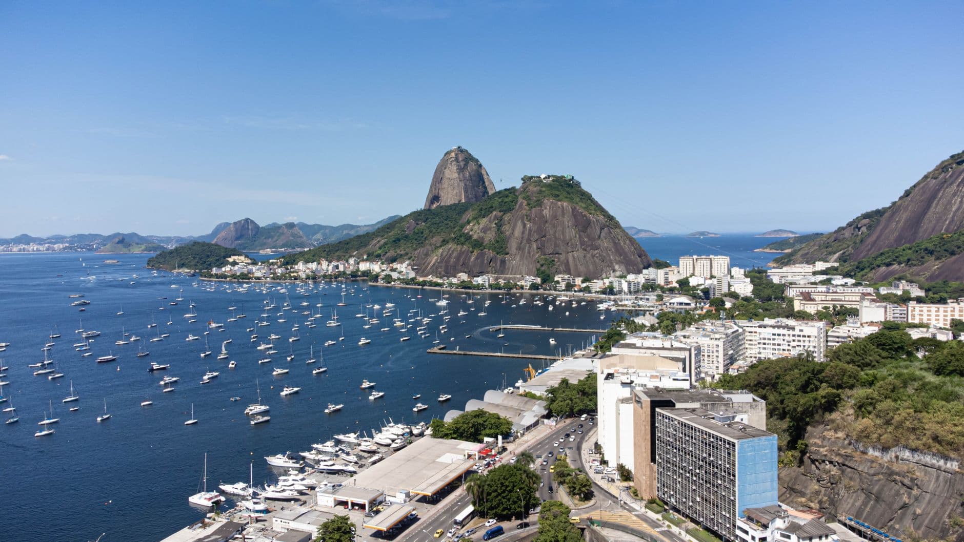 Stunning aerial view of Sugarloaf Mountain surrounded by navy sailboats on a clear day in Rio de Janeiro.