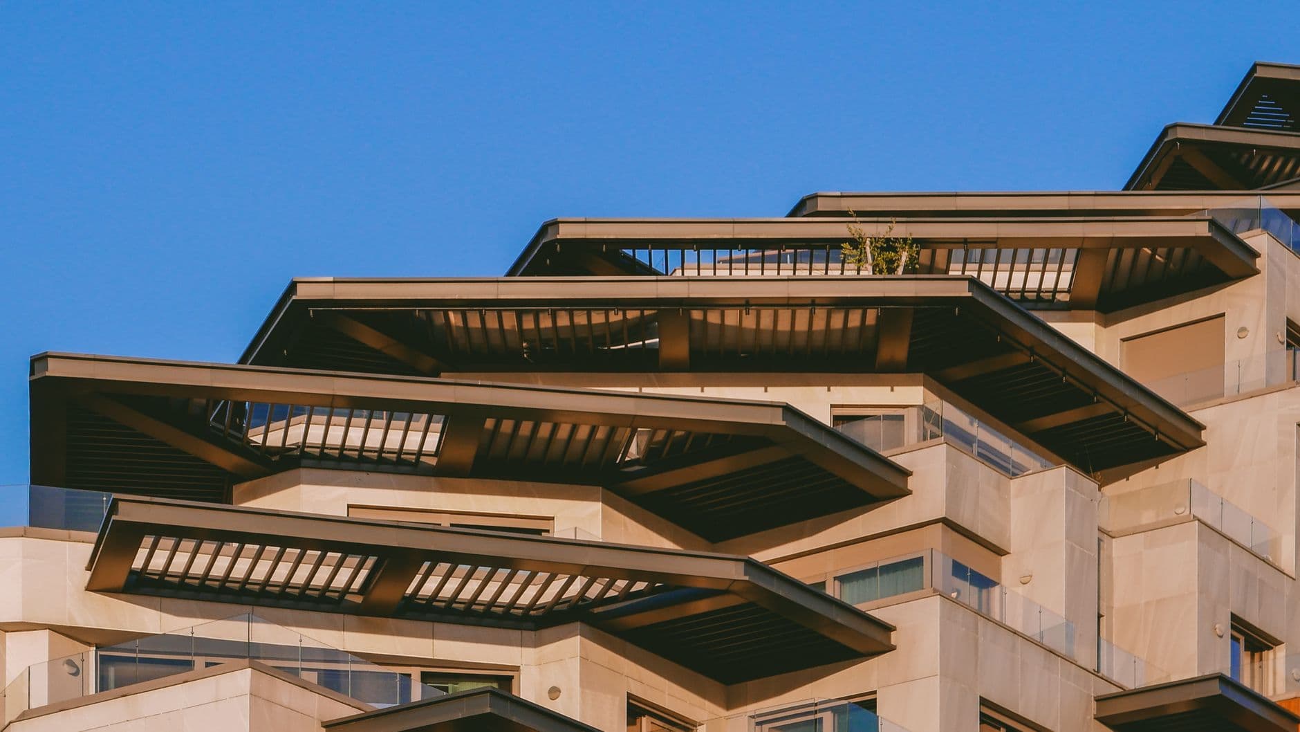 A stunning capture of a modern architectural building with sunlit balconies against a clear blue sky.