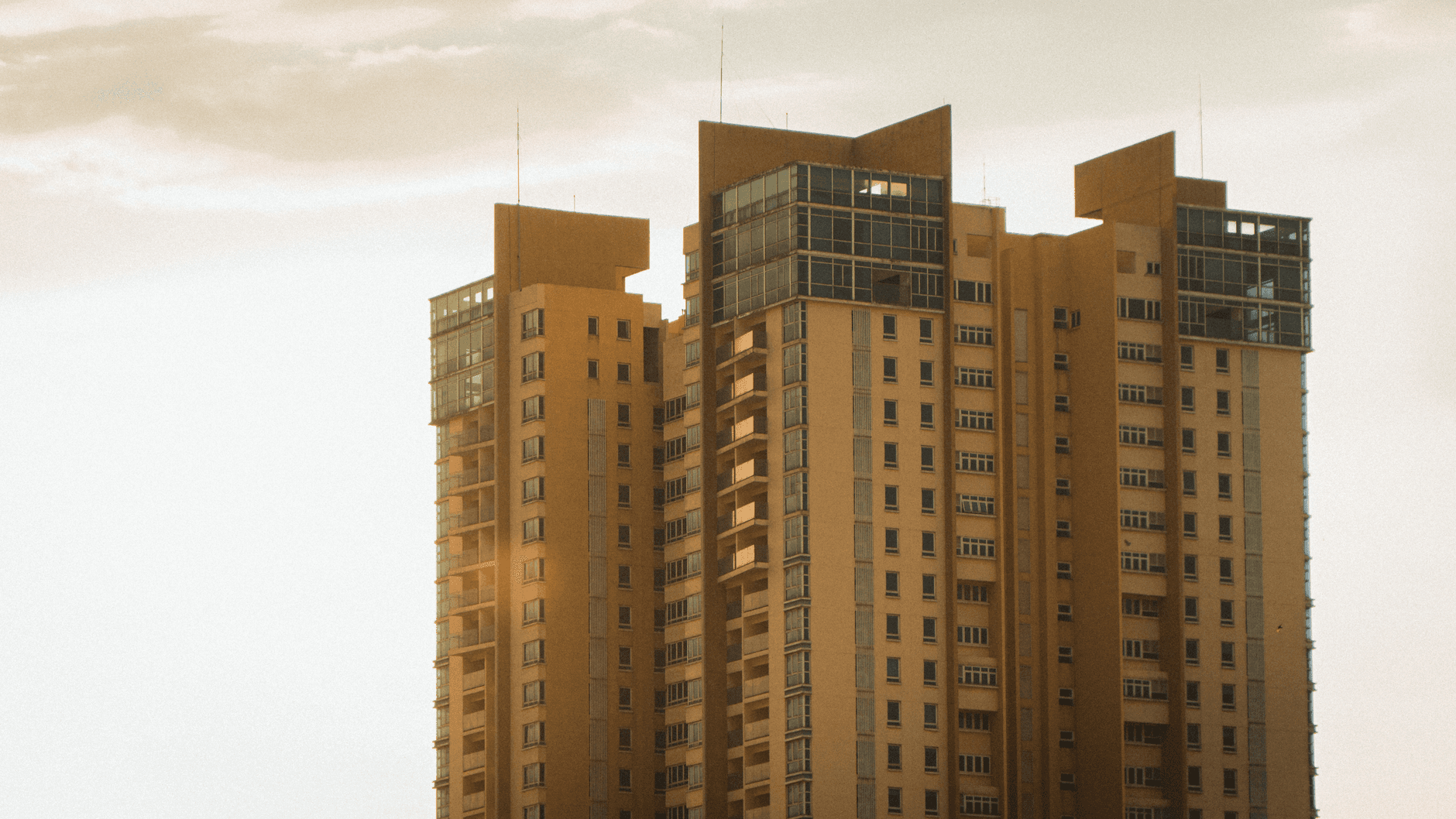 Urban high-rise building captured at sunset with warm tones and modern architecture.