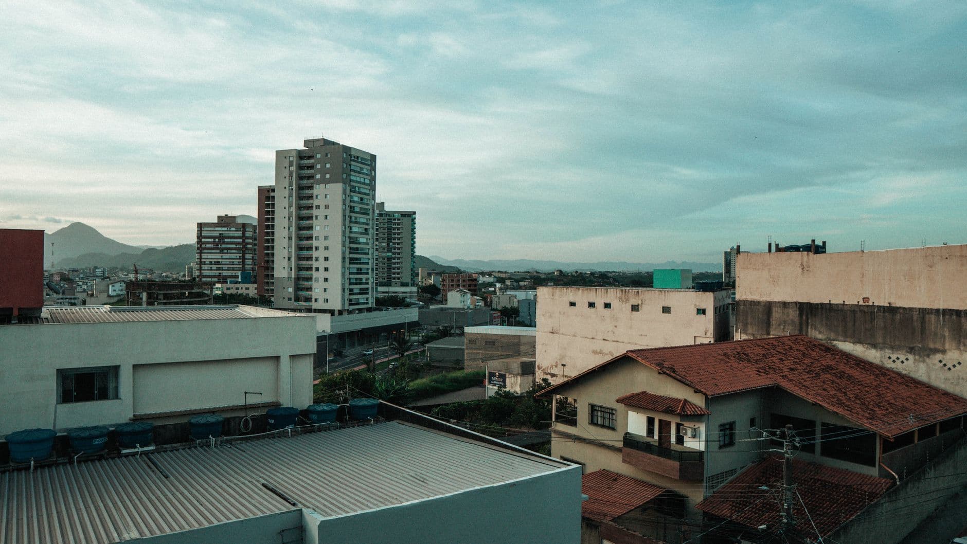 A cityscape view with residential houses and tall buildings under an overcast sky.