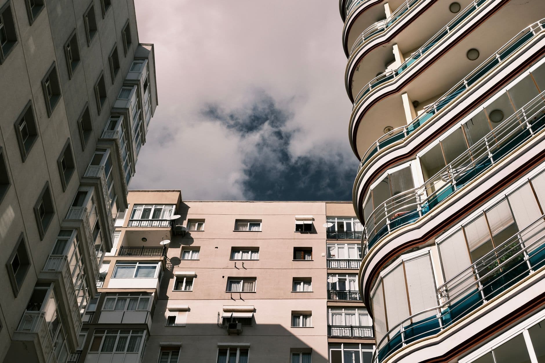 A low-angle view of modern apartment buildings in İzmir, Türkiye against a cloudy sky.