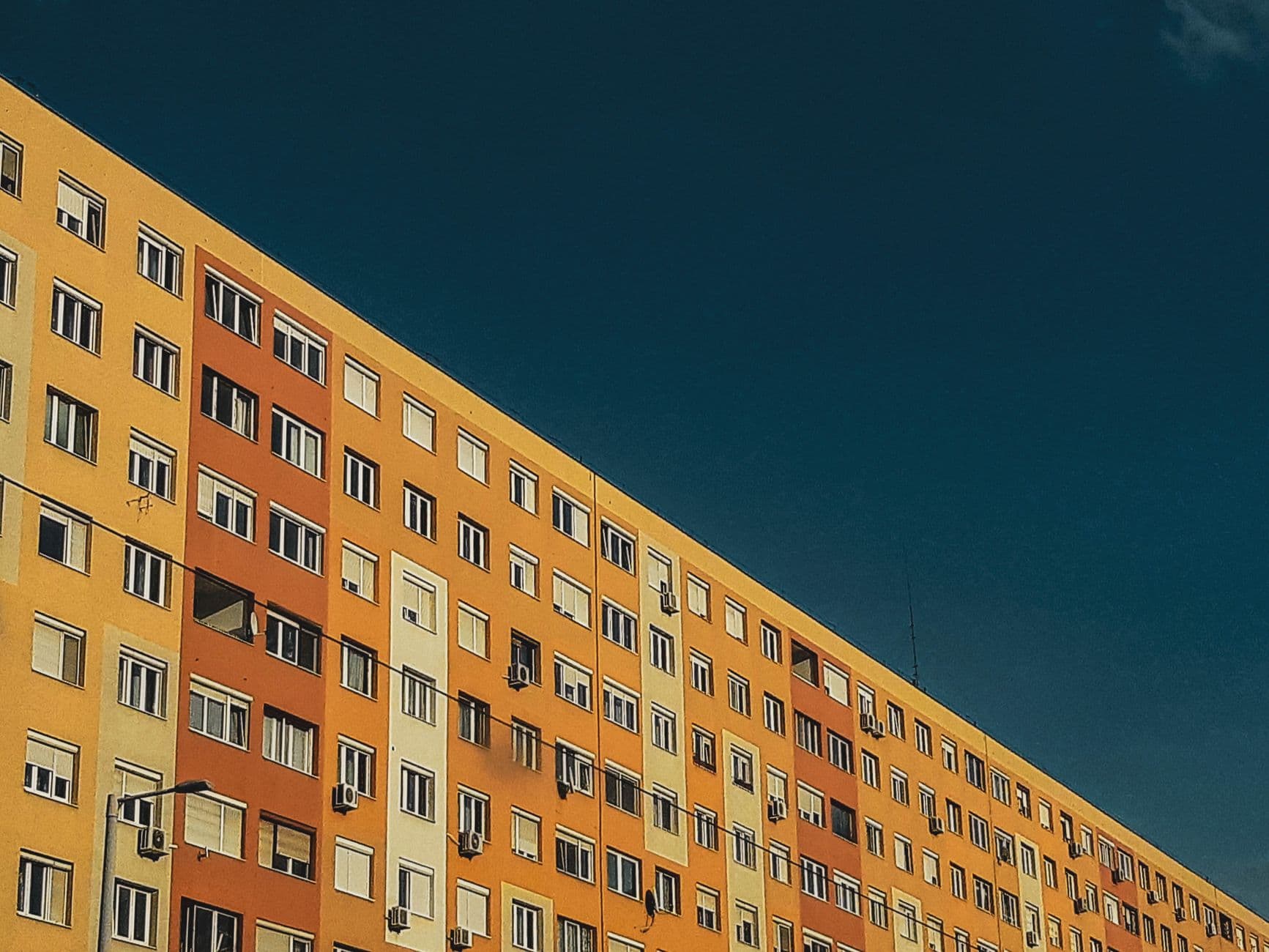 A vibrant urban building with yellow and orange facade under a clear sky.
