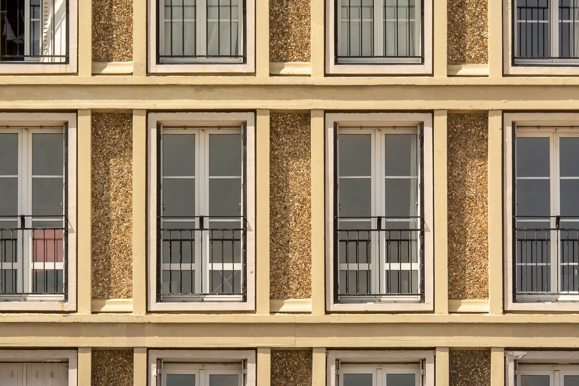 Front view of modern apartment facade with symmetrical windows and balconies.