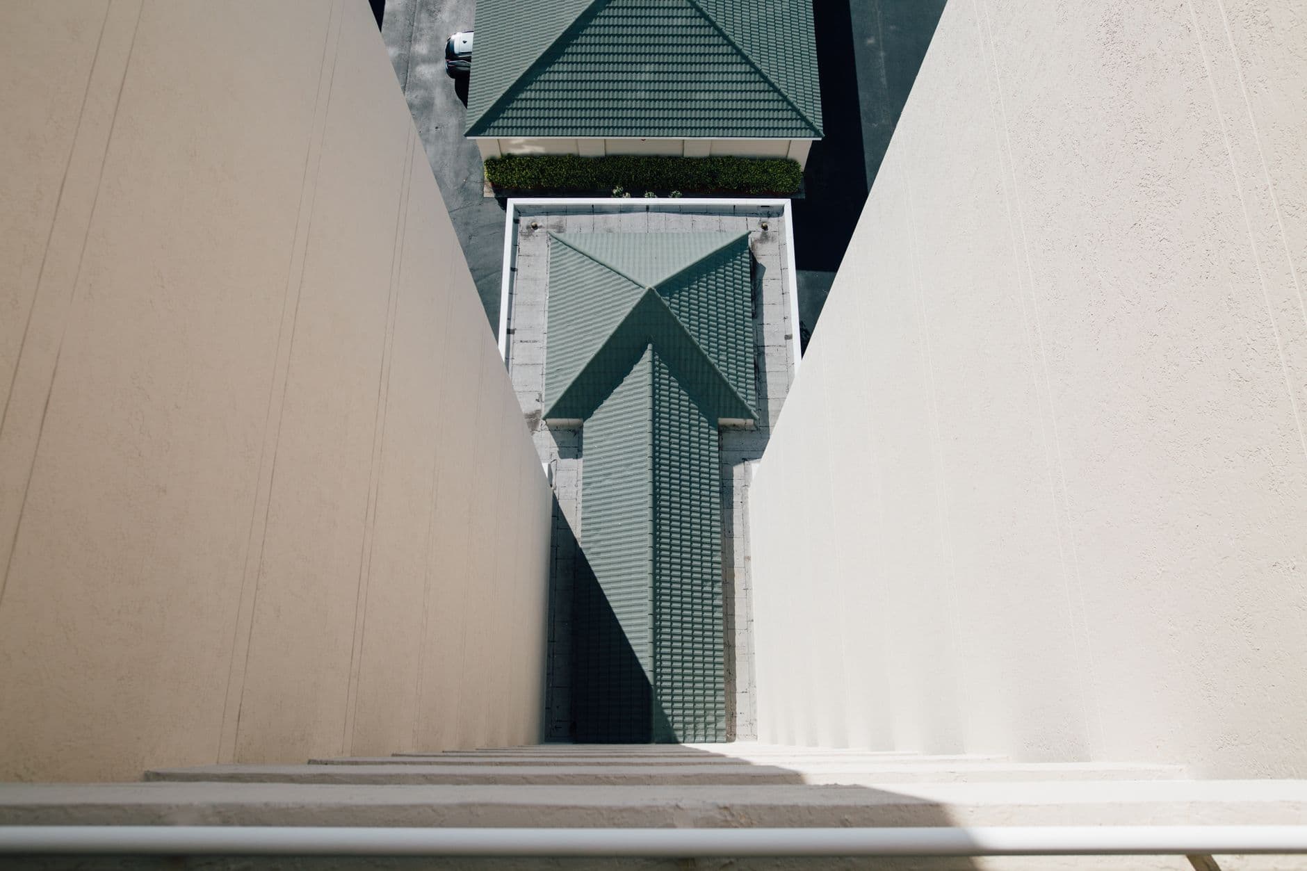 From above of concrete walls and green tile roof of modern building on sunny day