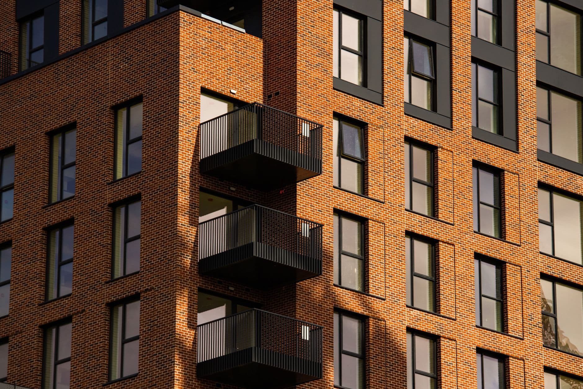 A striking view of a modern brick apartment facade with dark metal balconies in Dublin.