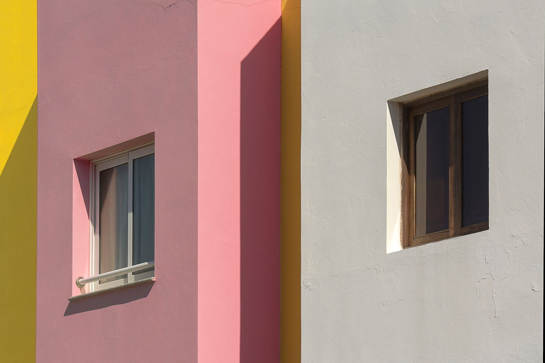A vibrant facade showcasing geometric shapes and varied window designs under sunlight.