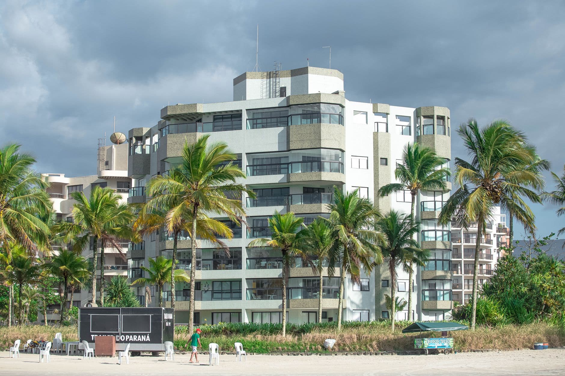 Contemporary beachfront architecture surrounded by lush palm trees on a cloudy day.