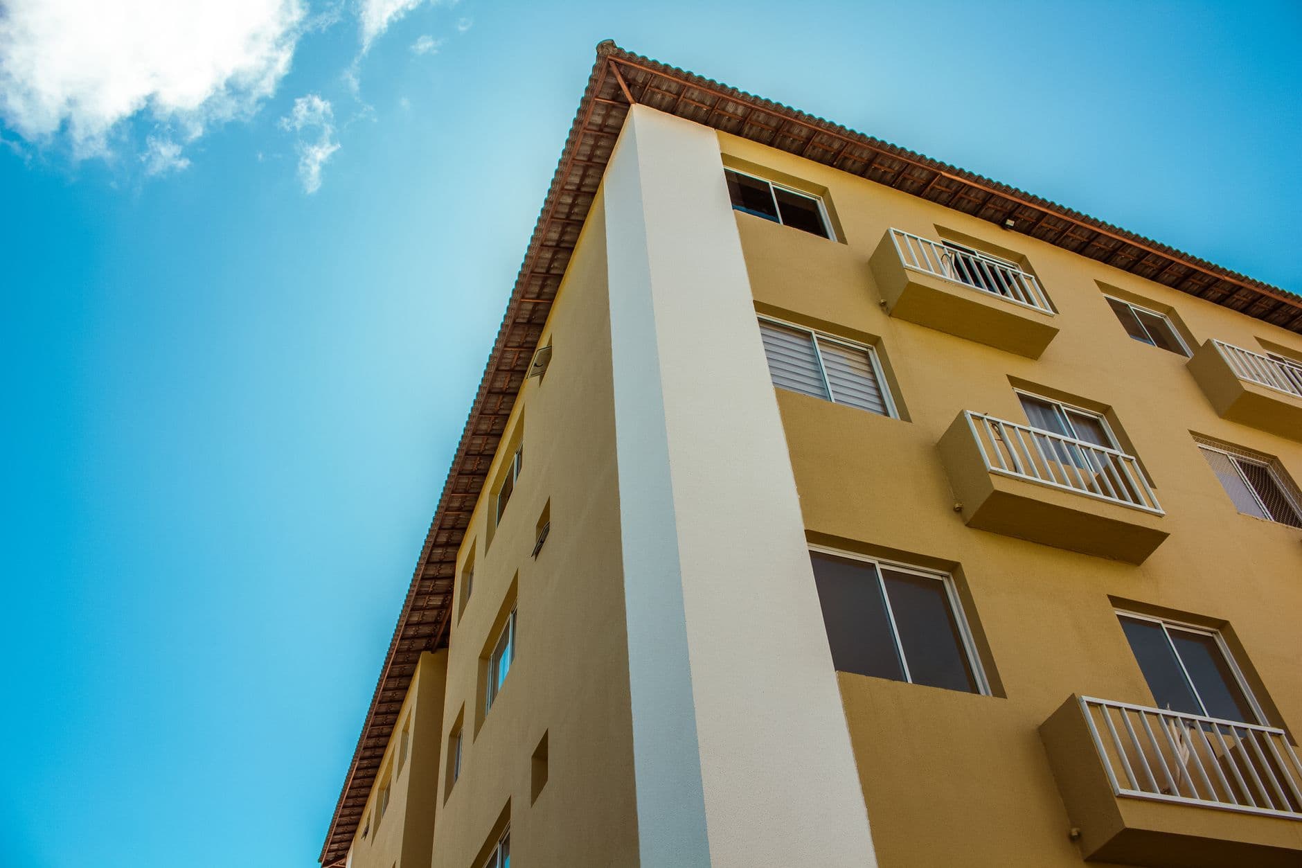 Close-up of a yellow residential building facade against a clear blue sky.