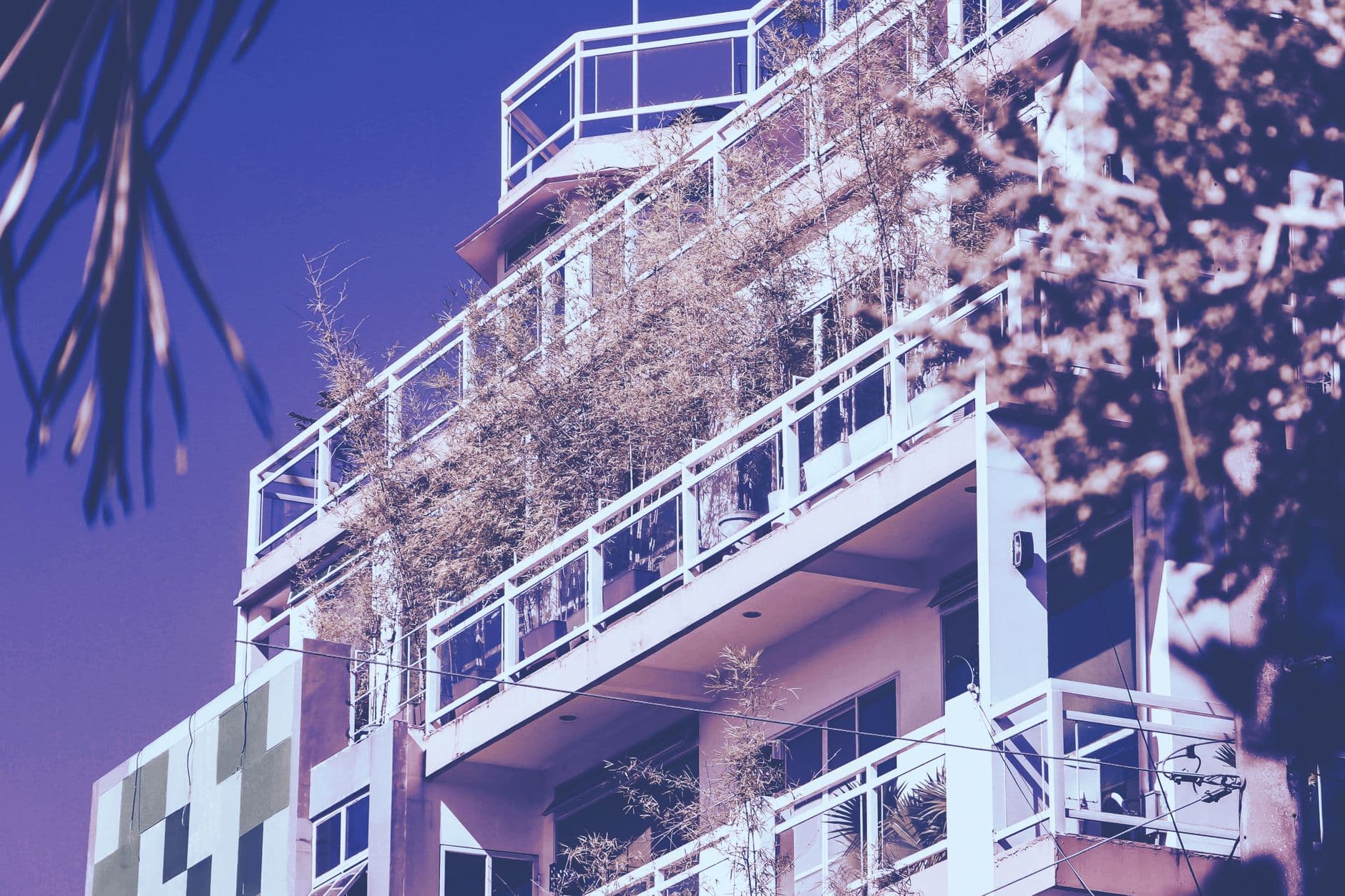 A modern multi-story building in the Philippines featuring greenery on balconies.