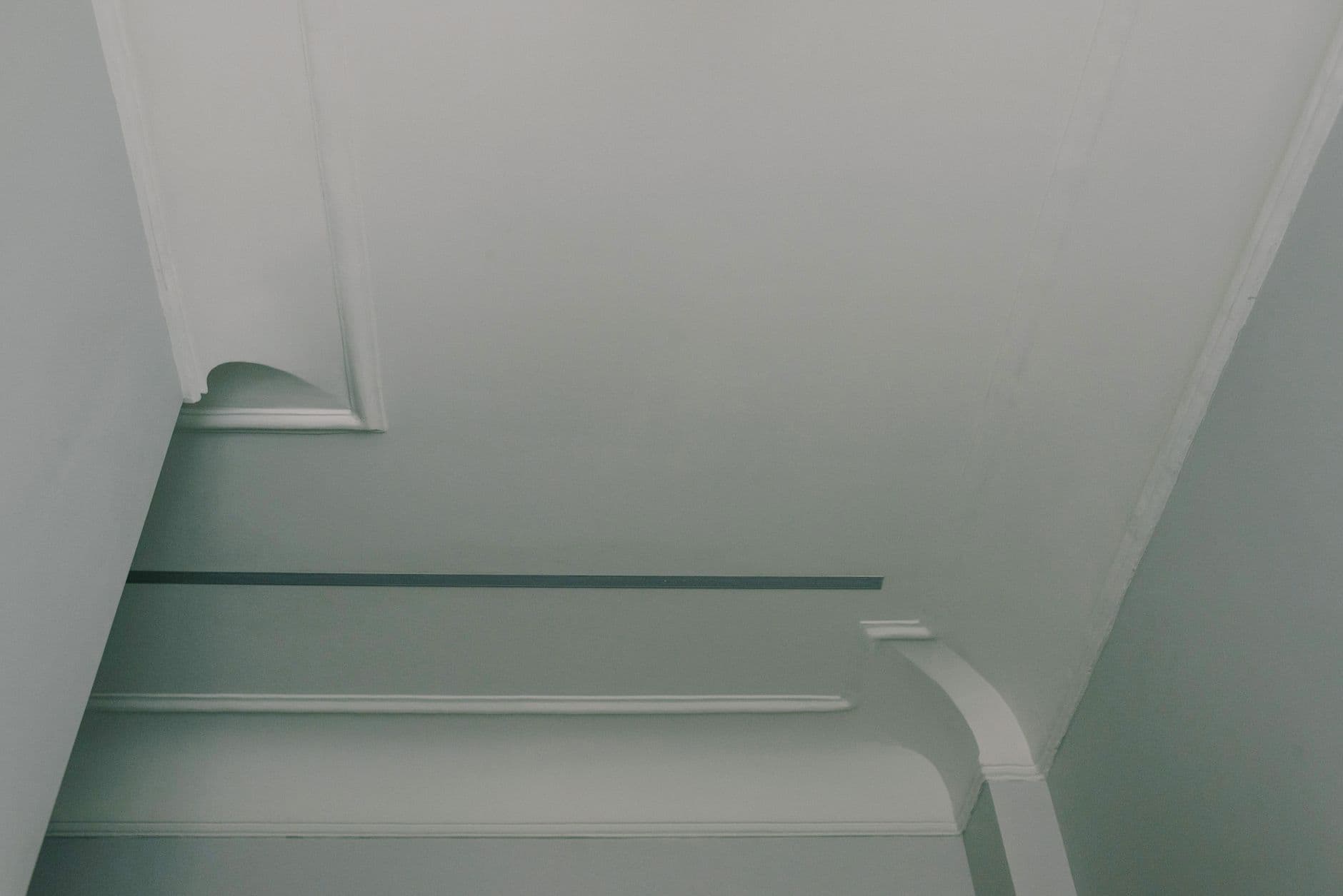 From below of light white ceiling with geometric ornament in stylish apartment in daytime
