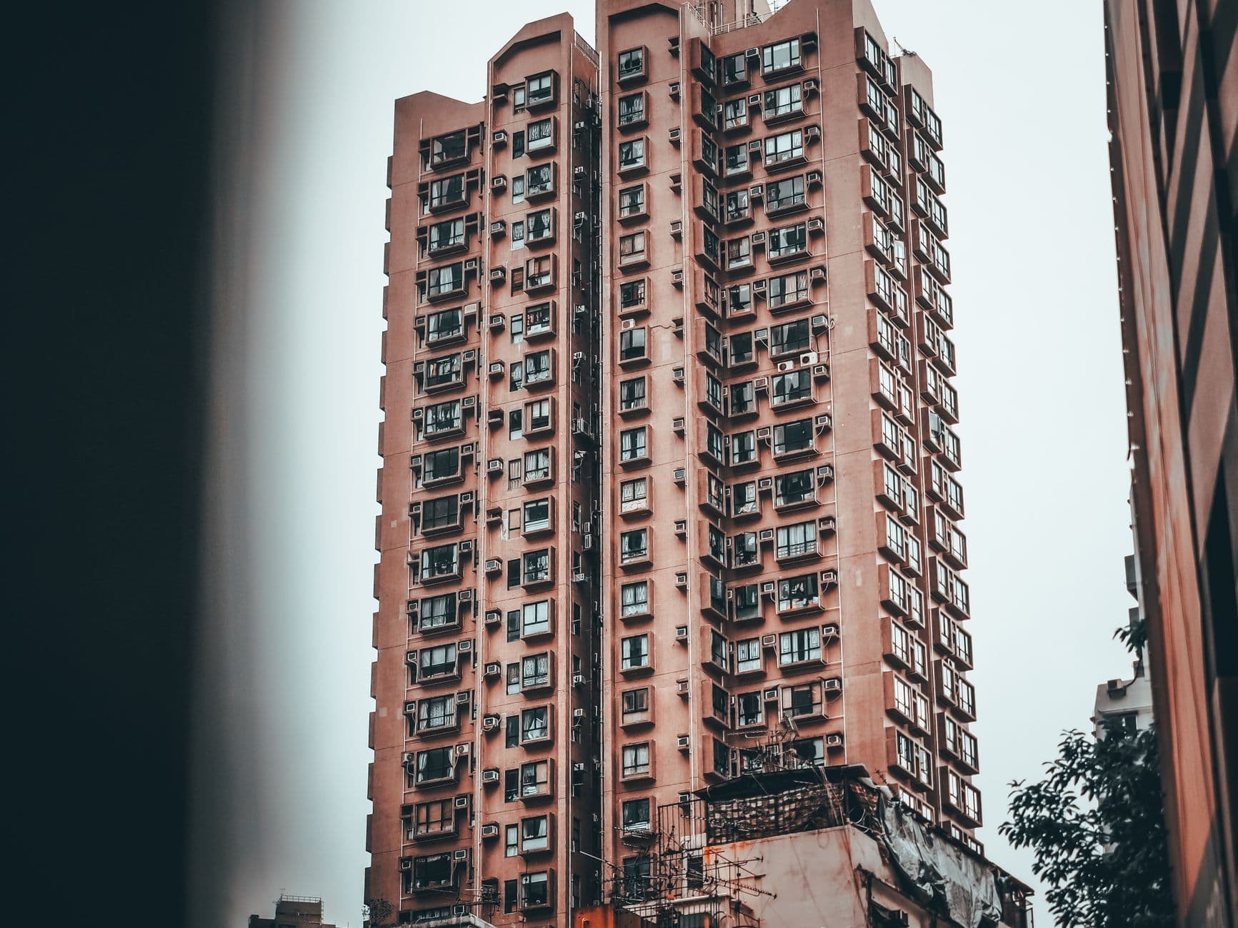 A tall urban apartment building with unique architecture and evening sky backdrop.