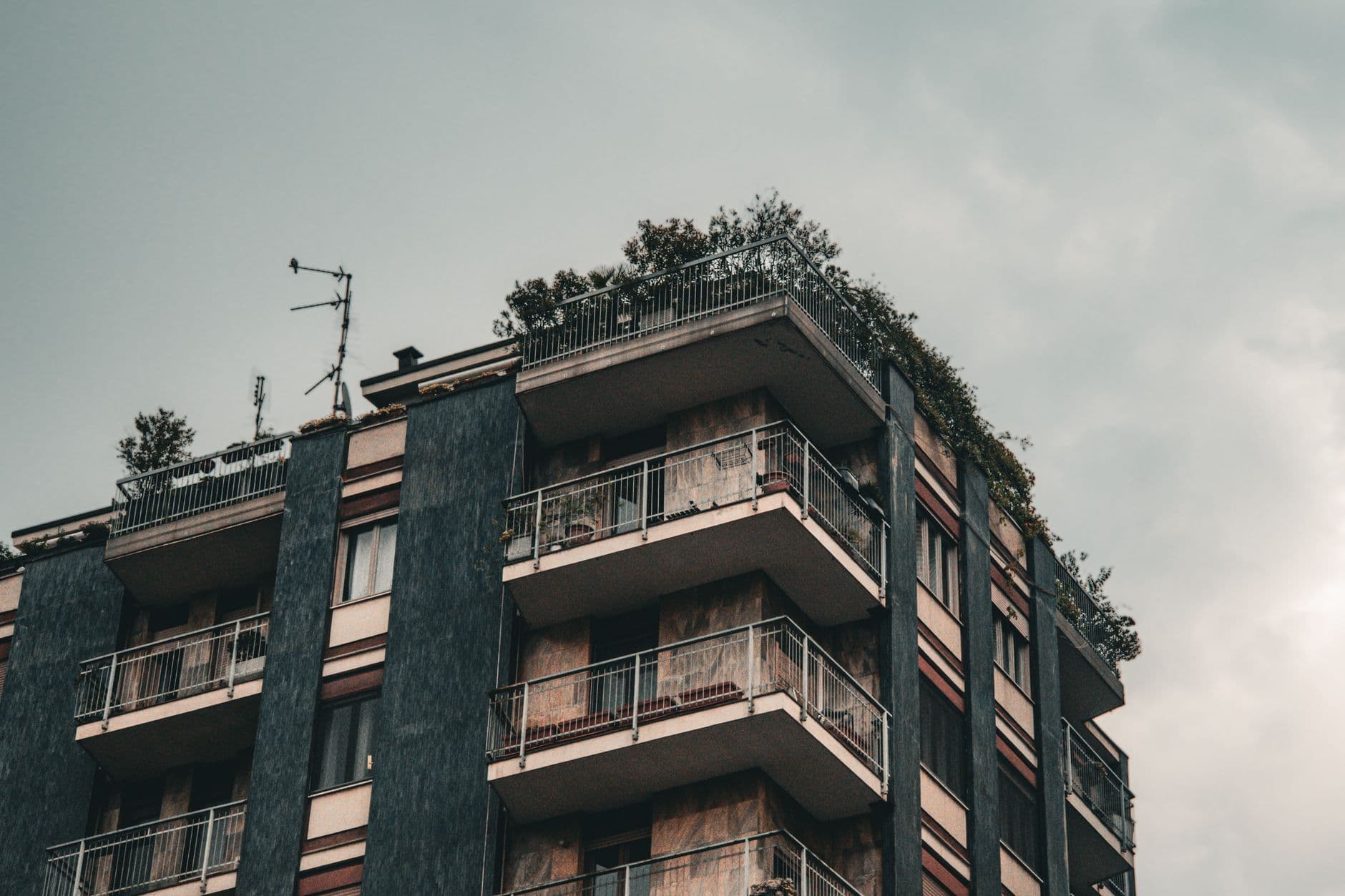 Urban building with balconies in Milan, showcasing modern architecture and a cloudy sky.