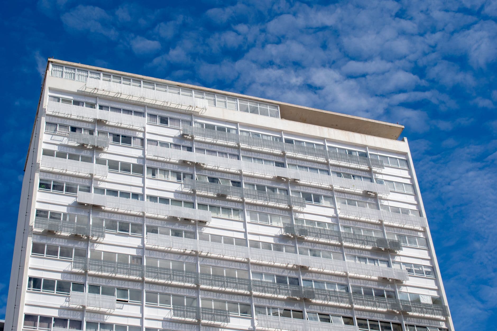 Contemporary apartment building under a bright blue sky in Brasilia, showcasing modern urban architecture.