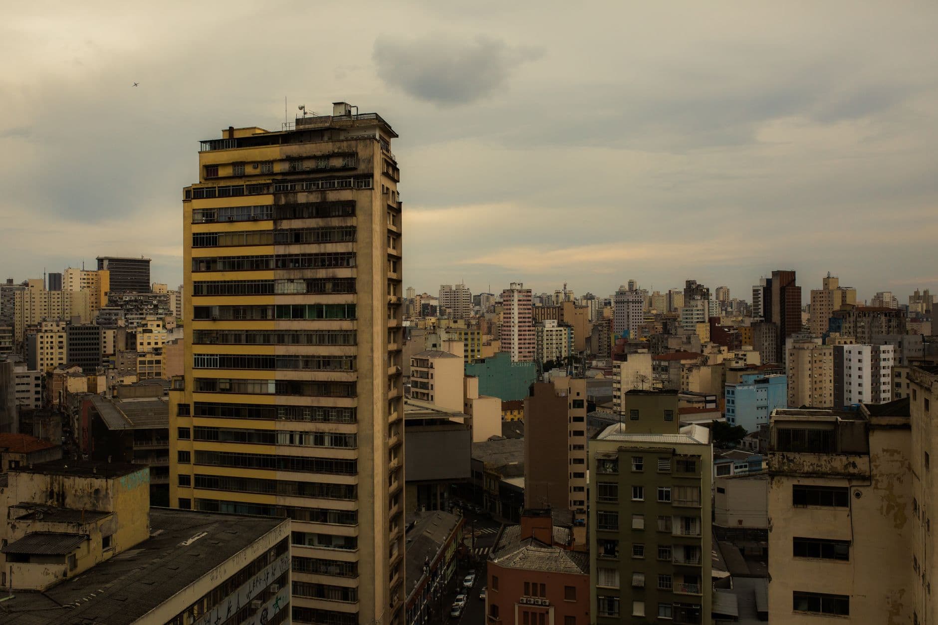 Aerial view of a cloudy urban skyline featuring diverse types of high-rise buildings.