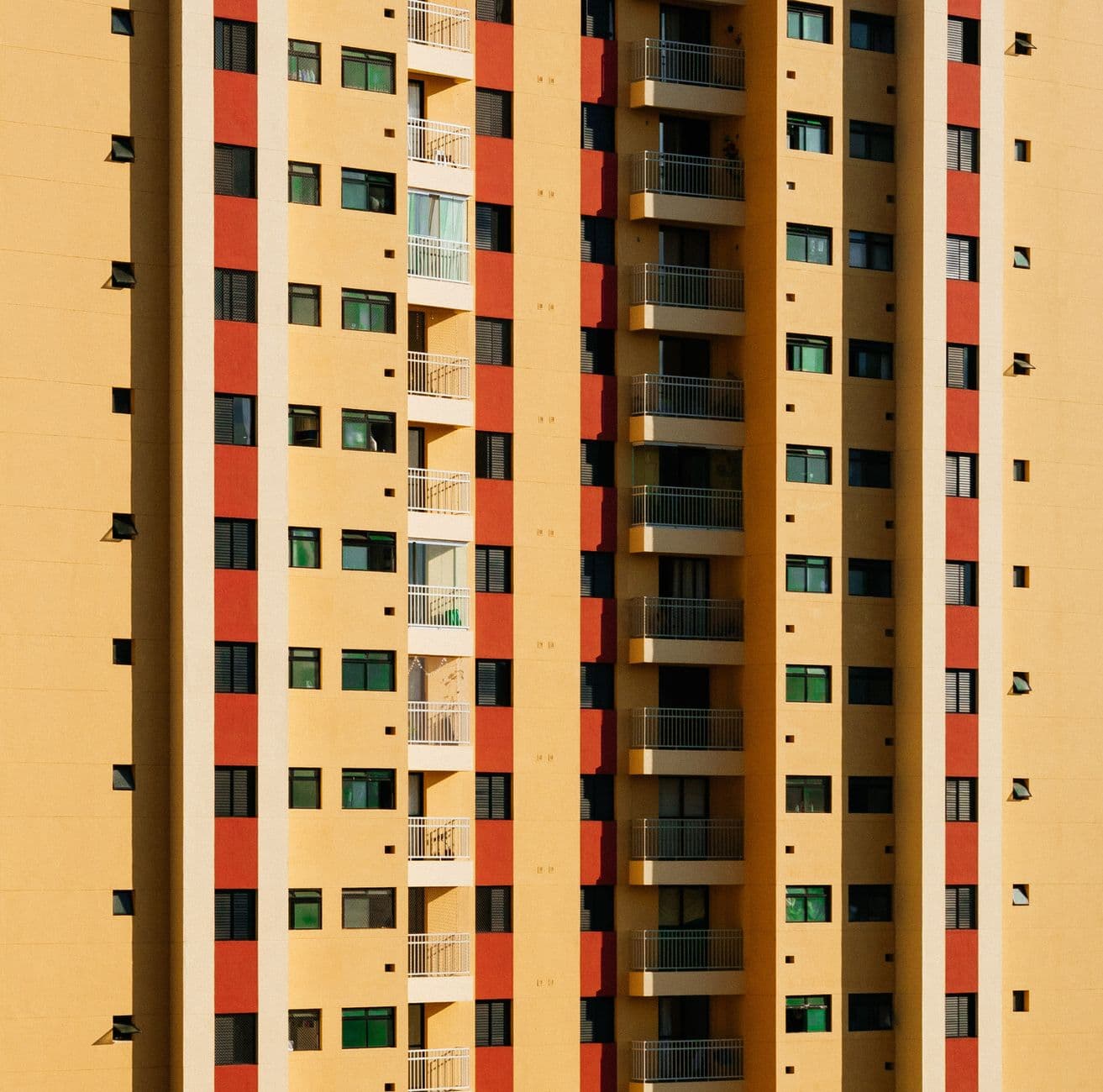 Close-up view of a contemporary high-rise building facade featuring a pattern of balconies and colorful panels.