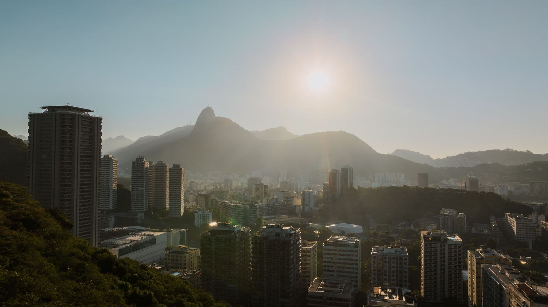 Aerial view of Rio de Janeiro's urban skyline at sunset, featuring Sugarloaf Mountain.
