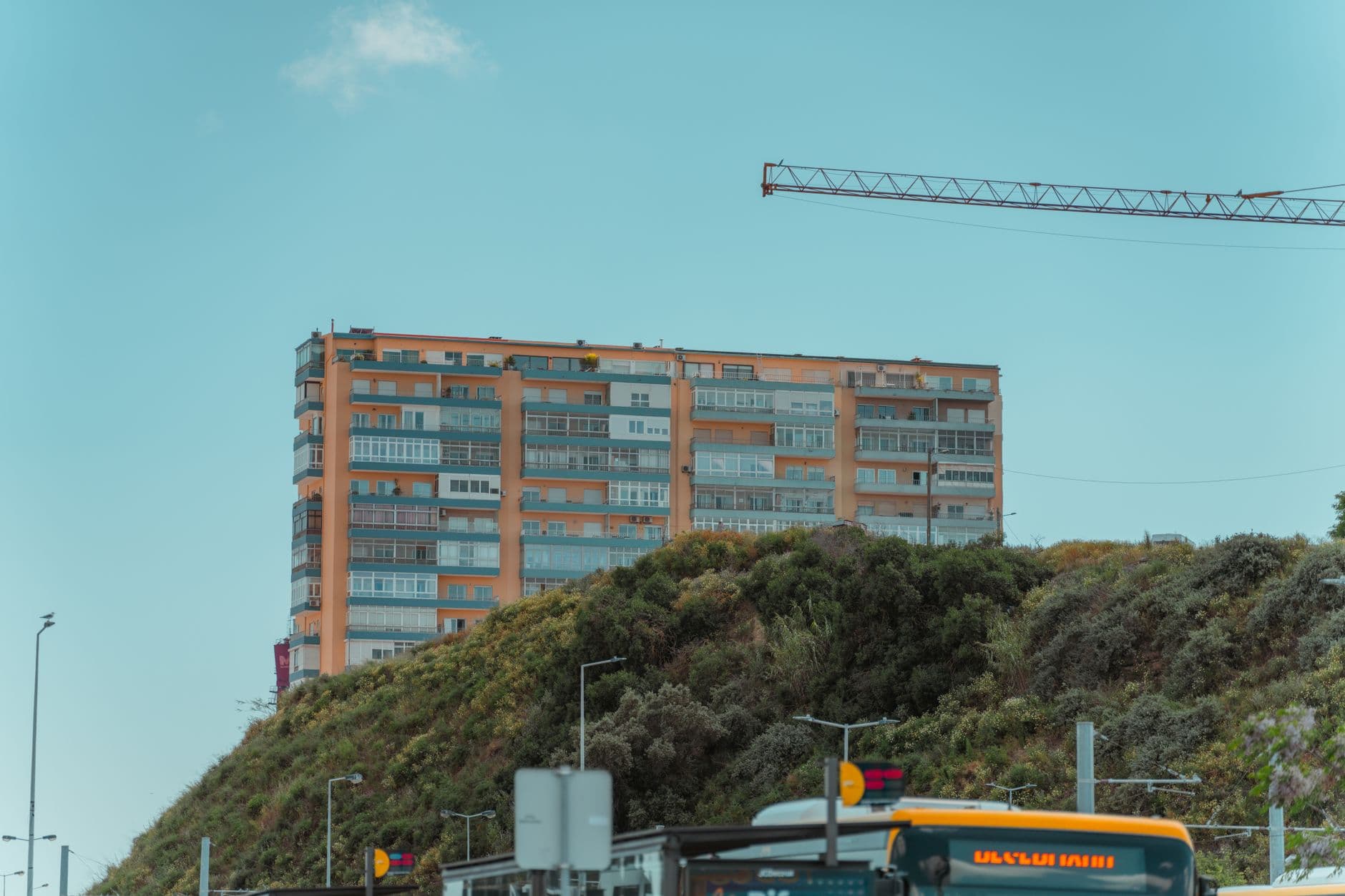 Contemporary apartment building with crane in Lisbon, Portugal under a clear blue sky.