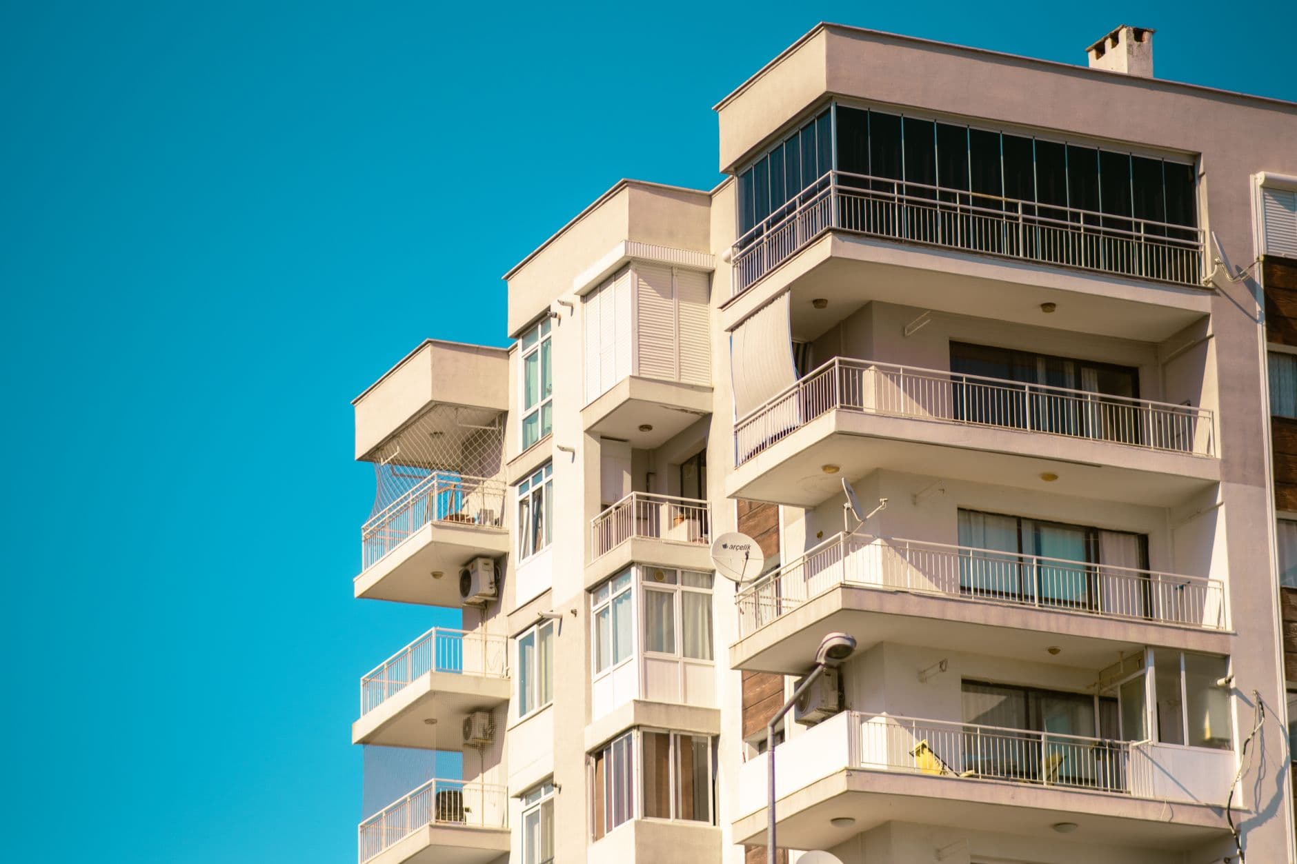 A modern apartment building with balconies in İzmir, Türkiye, under clear blue skies.